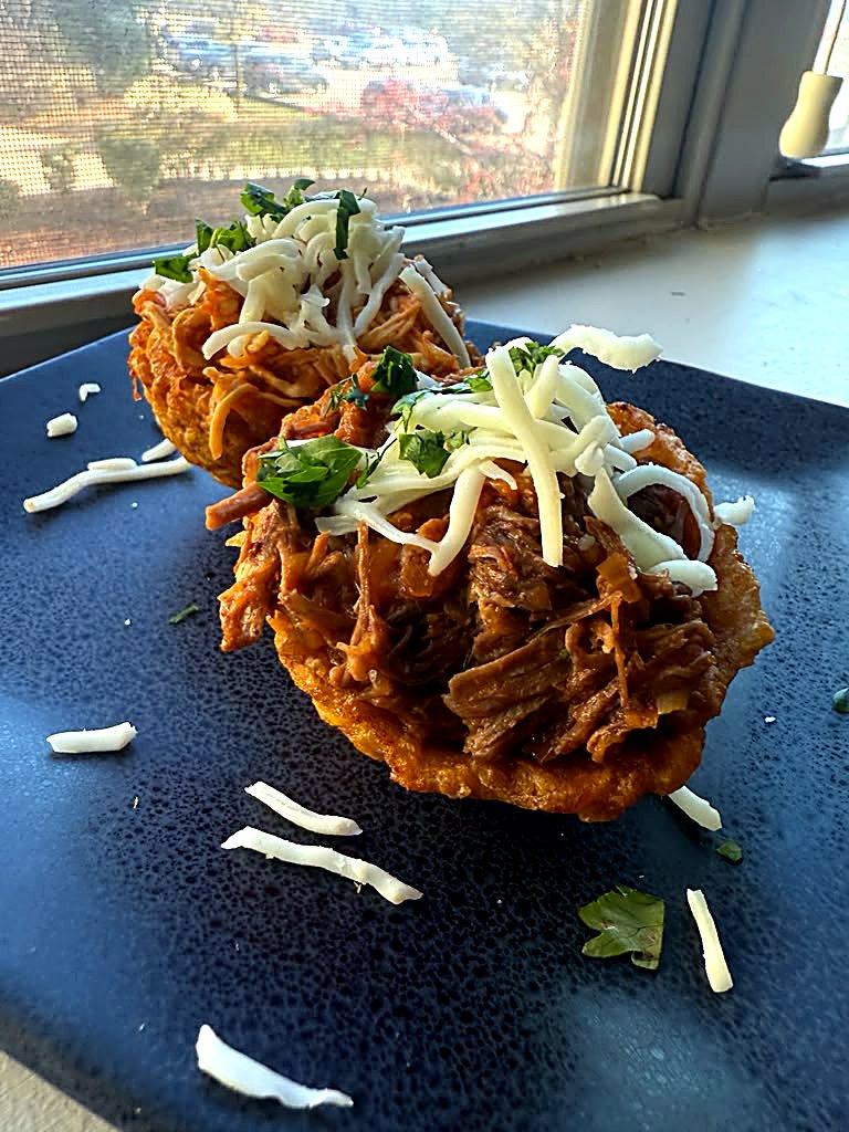 Tostón topped with shredded meat and cheese